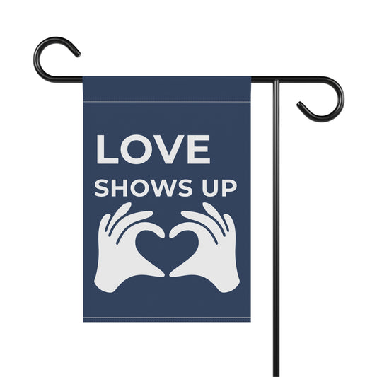 Garden flag with 'LOVE SHOWS UP' text and heart hands design on a blue background.
