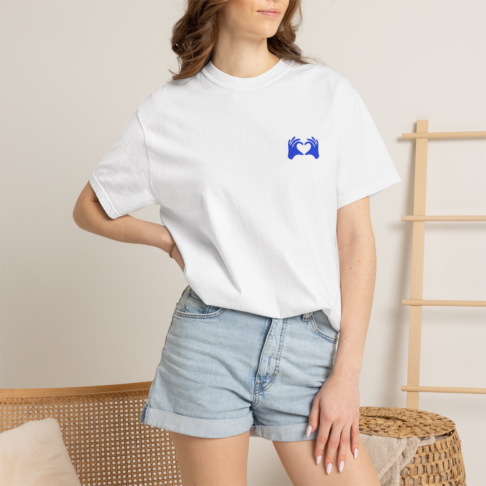 Person wearing a white t-shirt with a graphic design and text, standing against a neutral background.