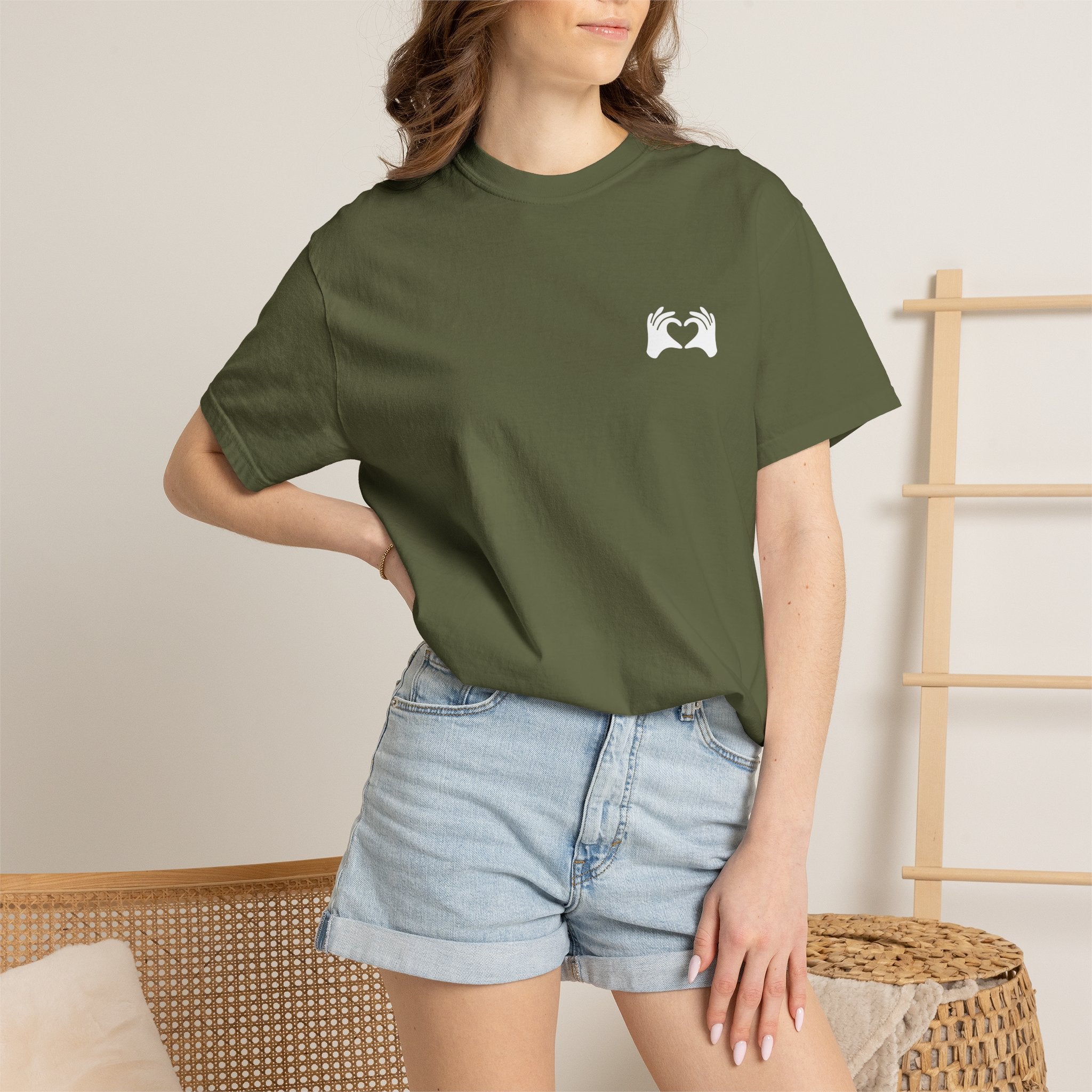 Person wearing a green t-shirt with 'Off Hours' text and denim shorts indoors.