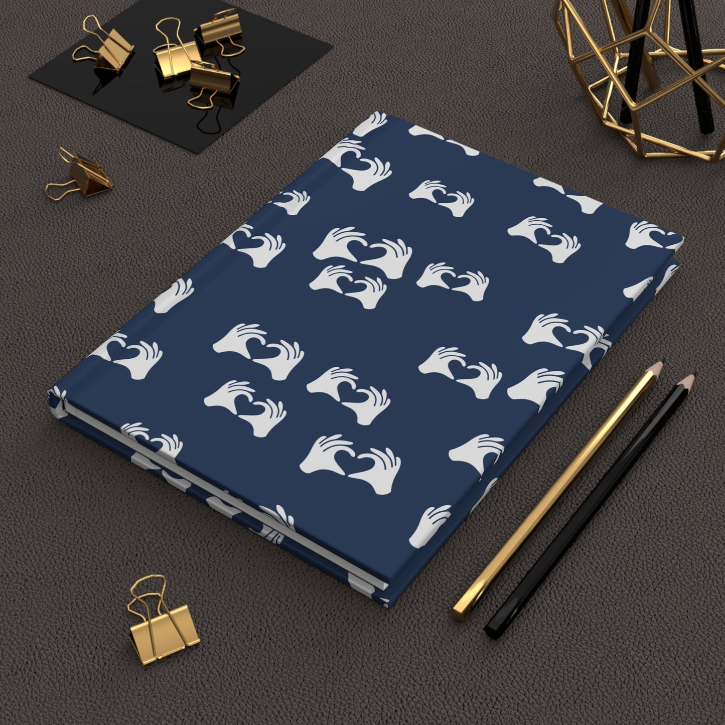 Blue notebook with white hand pattern on a dark surface with office supplies.