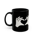 Black mug with white hand and heart design on a white background