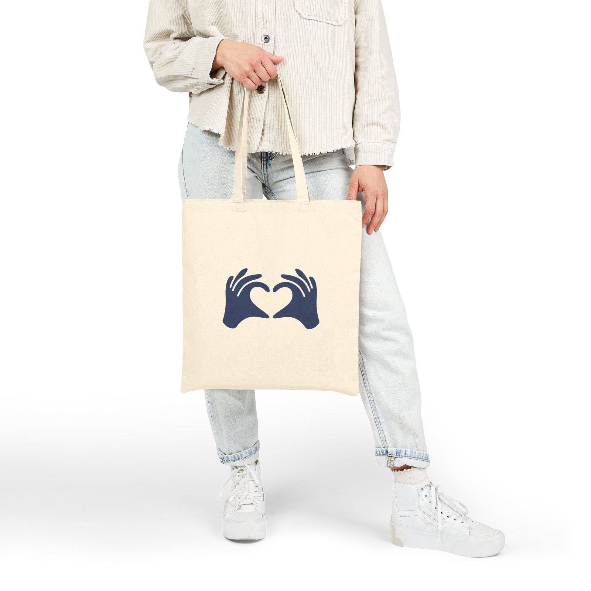 Person holding a tote bag with text and graphics on a white background