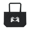 Black tote bag with white hands forming a heart design on a white background